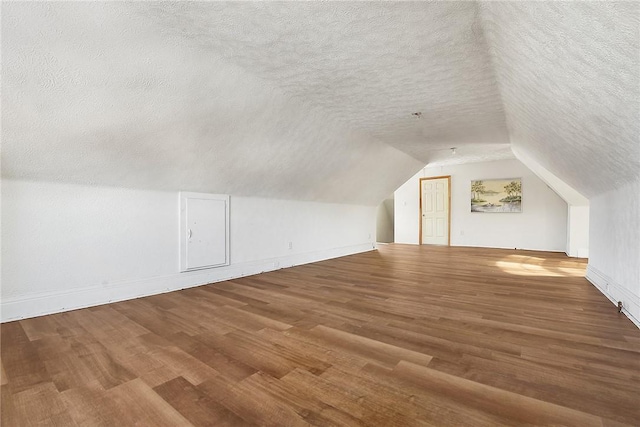 additional living space featuring wood-type flooring, a textured ceiling, and lofted ceiling