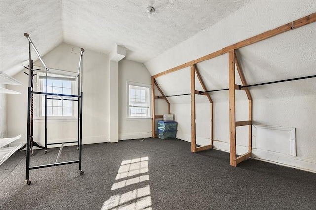 bonus room featuring vaulted ceiling, a textured ceiling, and dark colored carpet