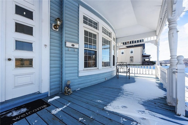 snow covered deck featuring a porch