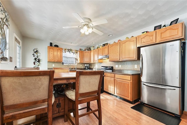 kitchen featuring ceiling fan, decorative backsplash, light wood-type flooring, range with electric cooktop, and stainless steel fridge