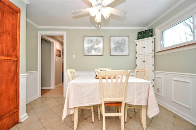 tiled dining area with ceiling fan and ornamental molding