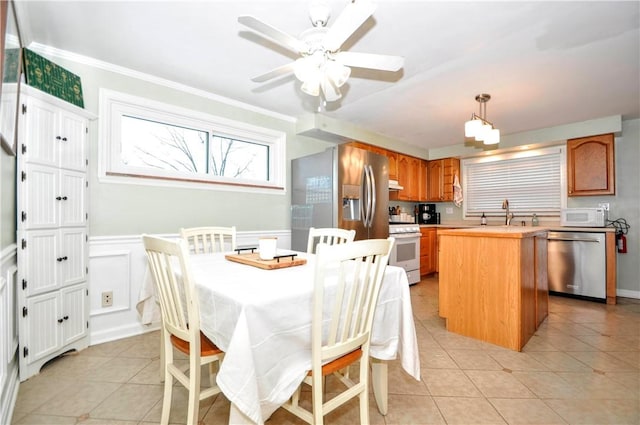 kitchen featuring ceiling fan, appliances with stainless steel finishes, light tile patterned flooring, and a center island