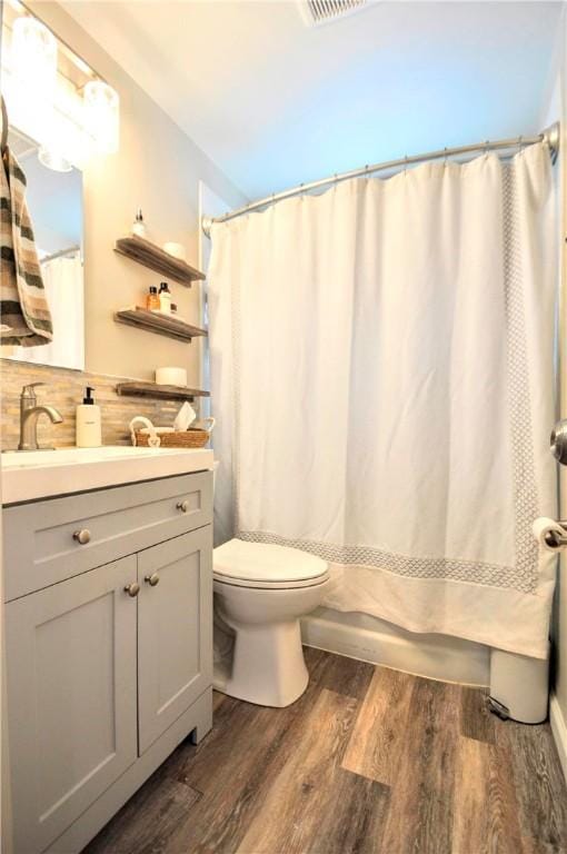 bathroom featuring hardwood / wood-style flooring, toilet, vanity, and tasteful backsplash