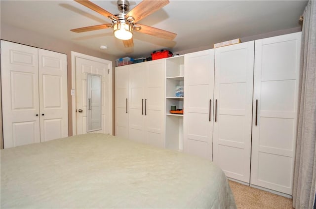 carpeted bedroom featuring ceiling fan and multiple closets