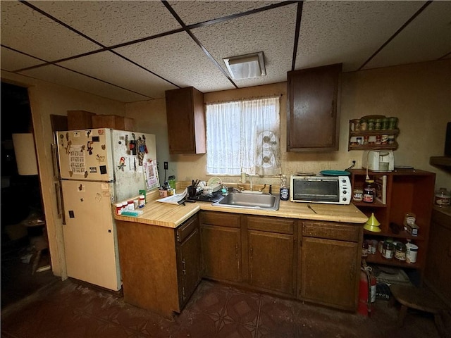 kitchen with a paneled ceiling, sink, and white refrigerator