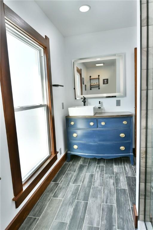 bathroom featuring a shower with shower door and vanity