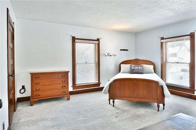 bedroom featuring light carpet, multiple windows, and a textured ceiling