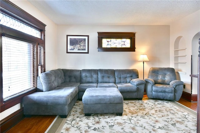 living room with hardwood / wood-style floors, built in features, and a textured ceiling