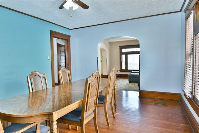 dining room with ceiling fan, a textured ceiling, ornamental molding, and hardwood / wood-style floors