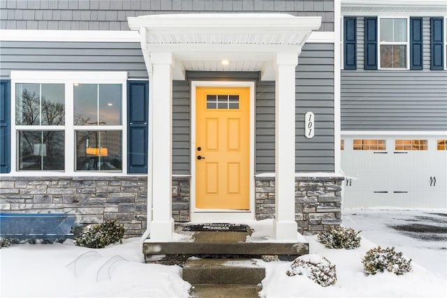 snow covered property entrance with a garage