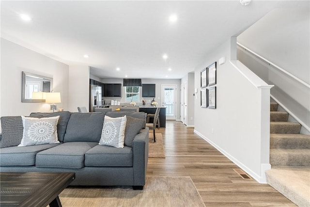 living area with visible vents, stairs, baseboards, recessed lighting, and light wood-style flooring