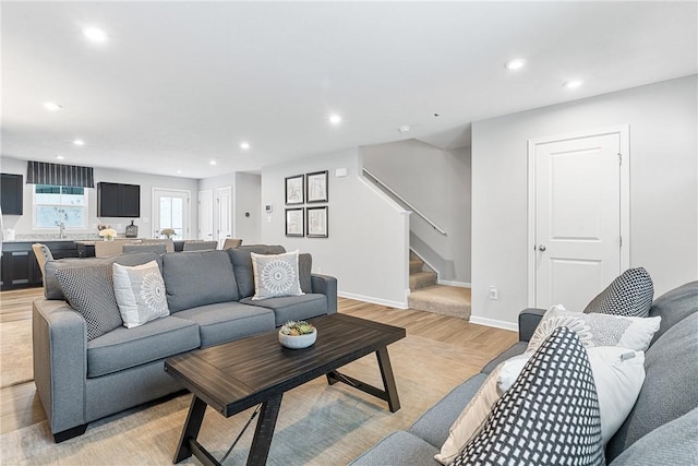 living area with light wood-type flooring, recessed lighting, baseboards, and stairway