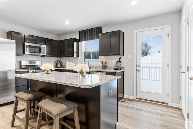 kitchen featuring light wood-type flooring, appliances with stainless steel finishes, a breakfast bar, and a kitchen island