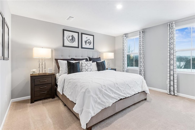 bedroom featuring visible vents, baseboards, multiple windows, and light carpet