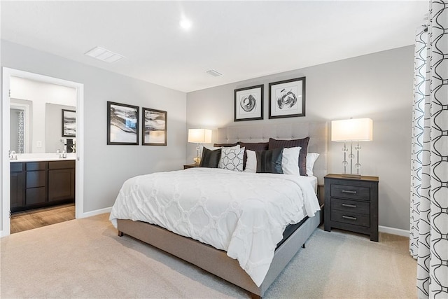 bedroom with baseboards, visible vents, light carpet, and ensuite bath