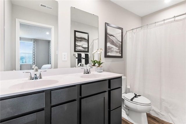 ensuite bathroom featuring a sink, toilet, double vanity, and visible vents