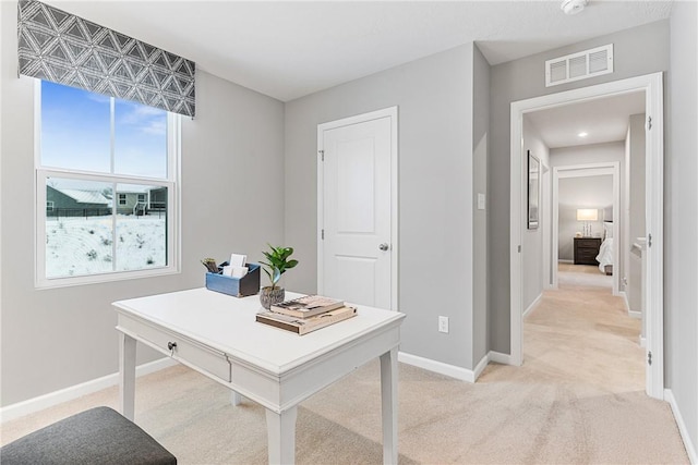 office space featuring baseboards, light colored carpet, and visible vents