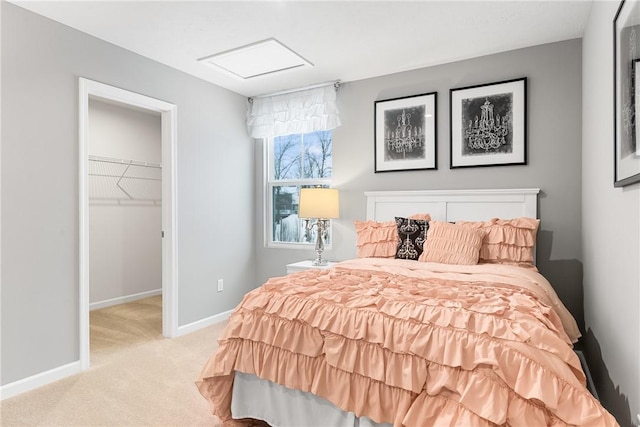 carpeted bedroom with a closet, a walk in closet, baseboards, and attic access