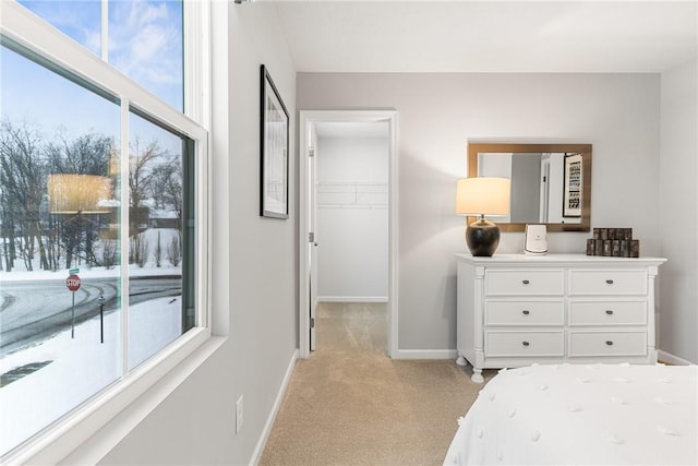 bedroom featuring baseboards, light colored carpet, a spacious closet, and a closet