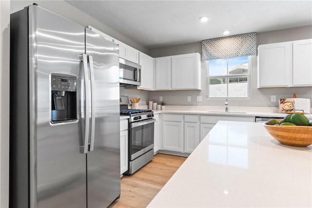 kitchen with light hardwood / wood-style floors, sink, white cabinets, and stainless steel appliances