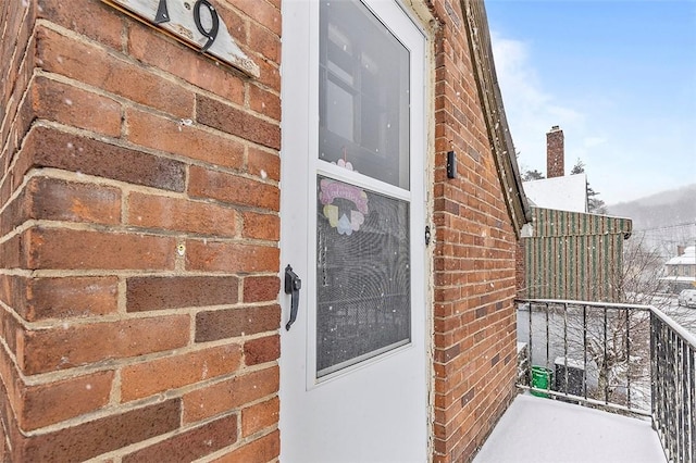 snow covered property entrance with a balcony