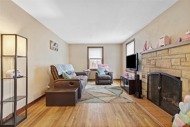 living room with light wood-type flooring and a stone fireplace