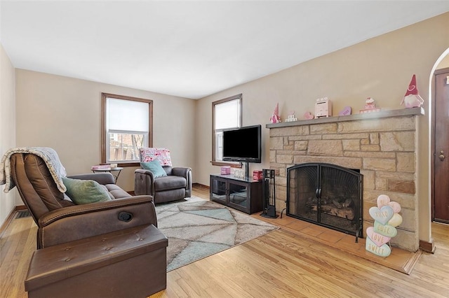 living room with light wood-type flooring and a stone fireplace