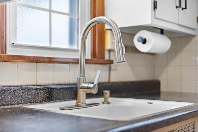 interior details featuring white cabinets, tasteful backsplash, and sink