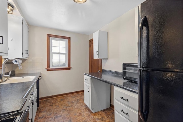 kitchen with decorative backsplash, black refrigerator, white cabinets, and sink