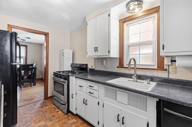 kitchen with ceiling fan, black fridge, gas range, white cabinets, and sink