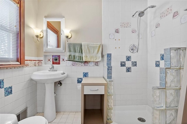 bathroom featuring toilet, tile walls, plenty of natural light, and a tile shower