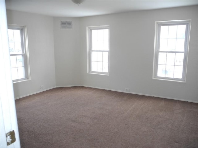 carpeted spare room featuring plenty of natural light