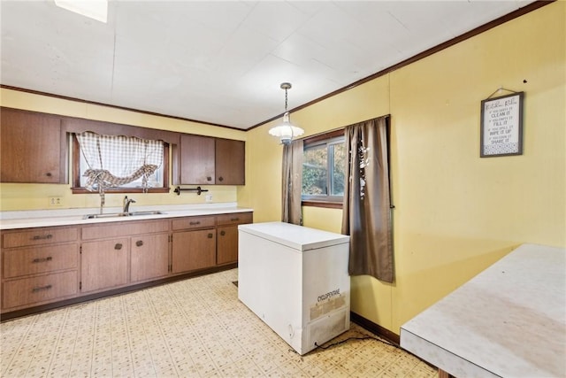 kitchen featuring ornamental molding, pendant lighting, refrigerator, and sink