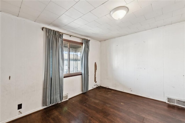 empty room featuring dark wood-type flooring and wooden walls