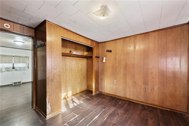 unfurnished bedroom with dark wood-type flooring and wooden walls