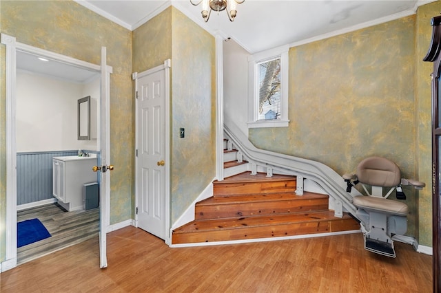 staircase featuring wood-type flooring, crown molding, and a chandelier