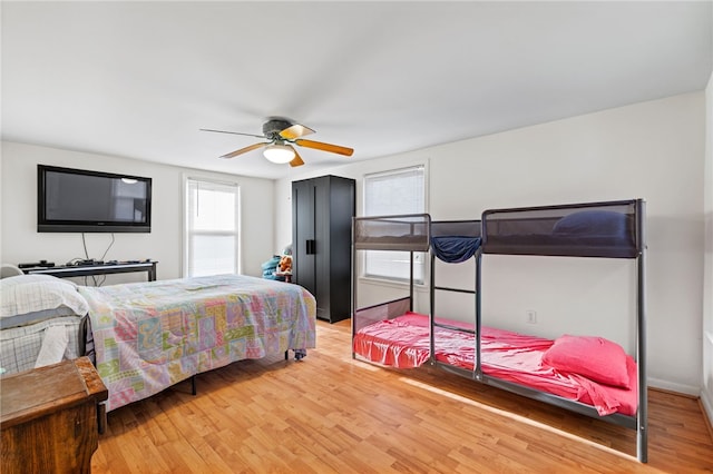 bedroom featuring ceiling fan, multiple windows, and hardwood / wood-style floors