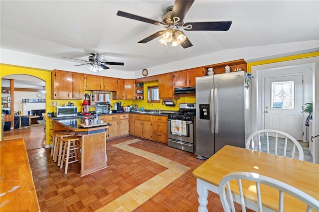 kitchen featuring ceiling fan, appliances with stainless steel finishes, a kitchen breakfast bar, light parquet flooring, and sink