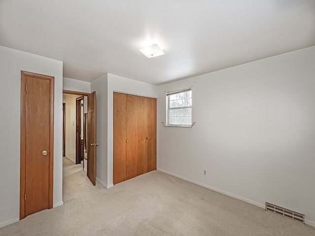 unfurnished bedroom with light colored carpet and a closet