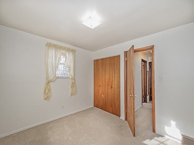 unfurnished bedroom with light carpet and a closet