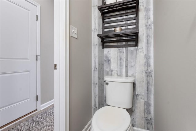 bathroom featuring toilet and wood walls