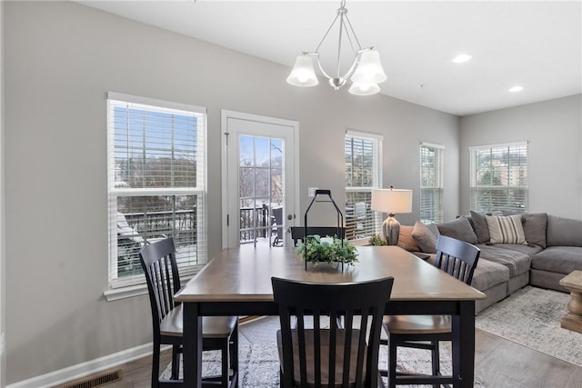 dining space featuring a wealth of natural light, an inviting chandelier, and hardwood / wood-style flooring