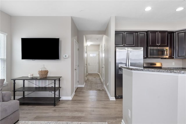 kitchen with light hardwood / wood-style floors, appliances with stainless steel finishes, dark brown cabinets, and a healthy amount of sunlight