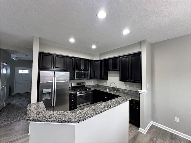 kitchen featuring a textured ceiling, a center island, dark hardwood / wood-style flooring, stainless steel appliances, and sink