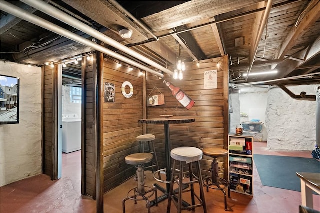 bar featuring wood walls, washer / dryer, and concrete flooring