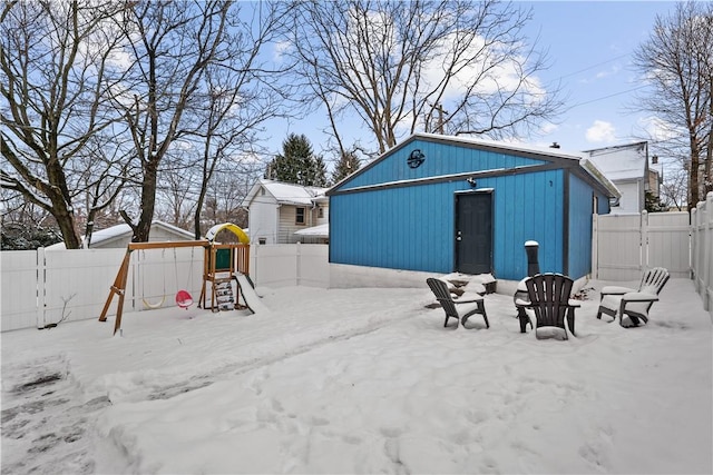 snowy yard featuring an outbuilding and a playground