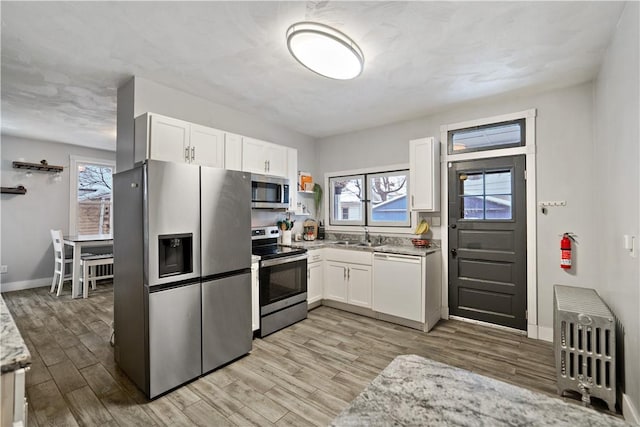 kitchen featuring appliances with stainless steel finishes, light hardwood / wood-style floors, and white cabinets