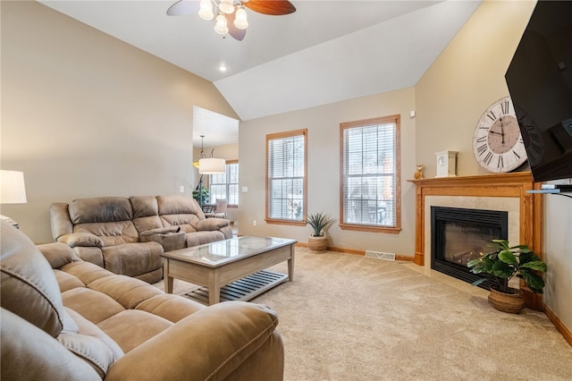 carpeted living room featuring ceiling fan, a tile fireplace, and lofted ceiling