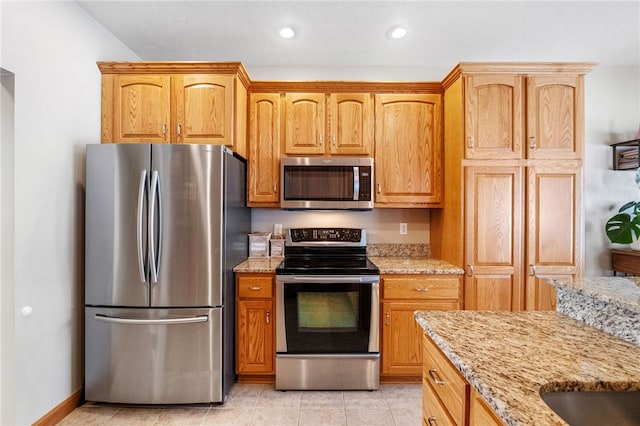 kitchen featuring appliances with stainless steel finishes, light tile patterned flooring, and light stone counters