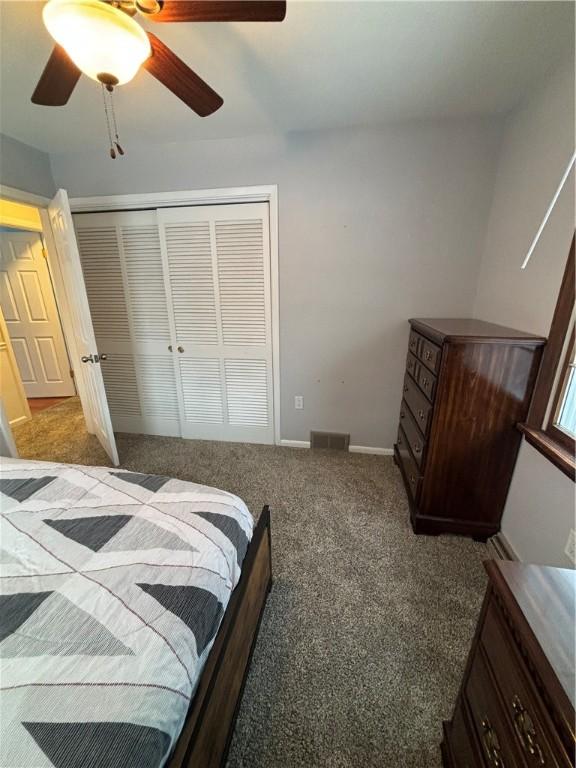 carpeted bedroom with ceiling fan and a closet